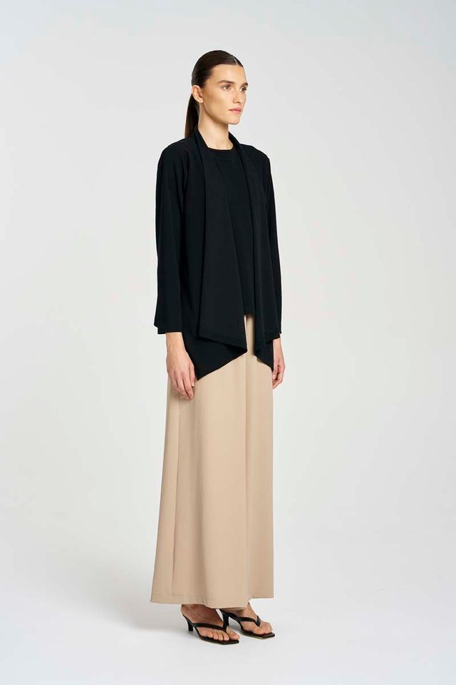 Woman wearing a black top and beige skirt on a white background