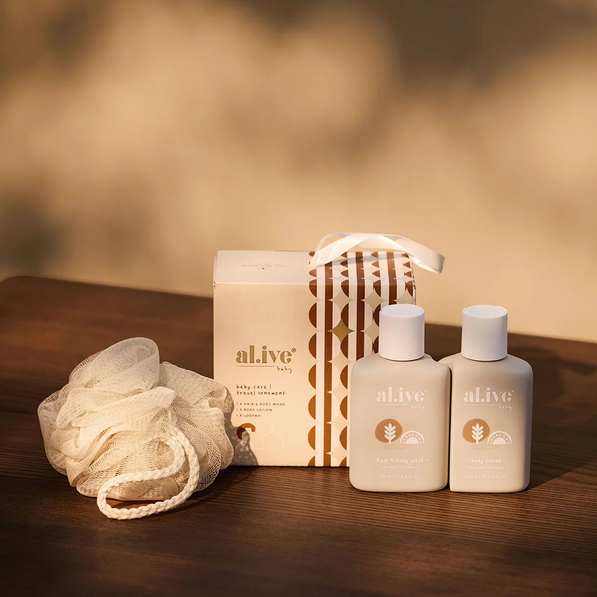 al.ive body Baby Care Travel Ornament with travel bottles and loofah on a timber table