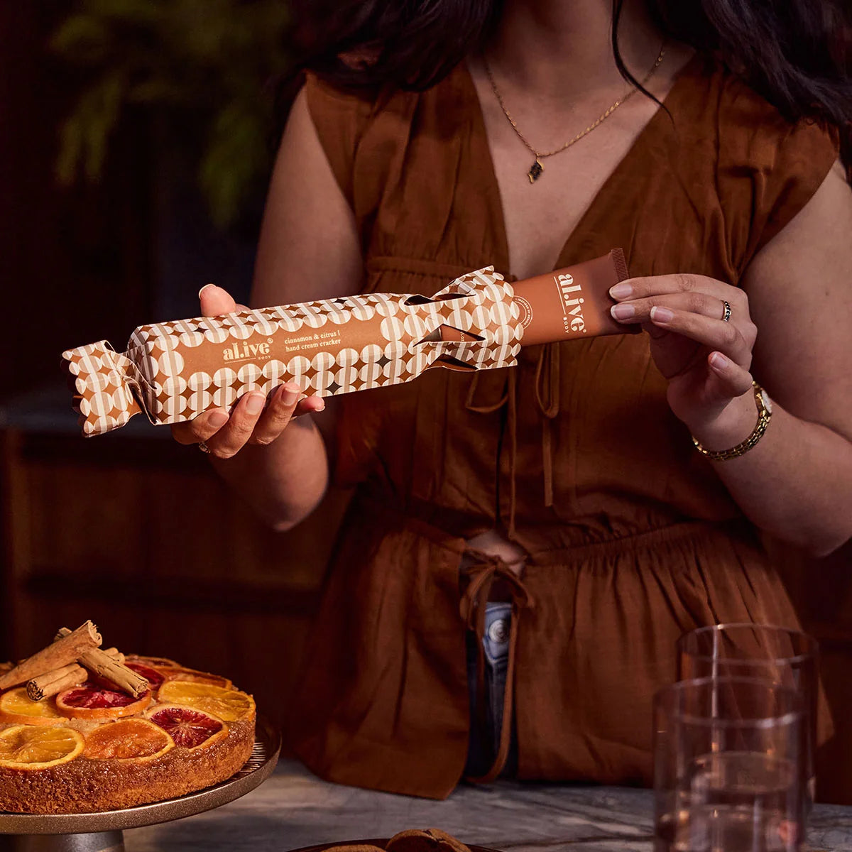 Woman holding the al.ive body Limited Edition Hand Cream Cracker at a Christmas table