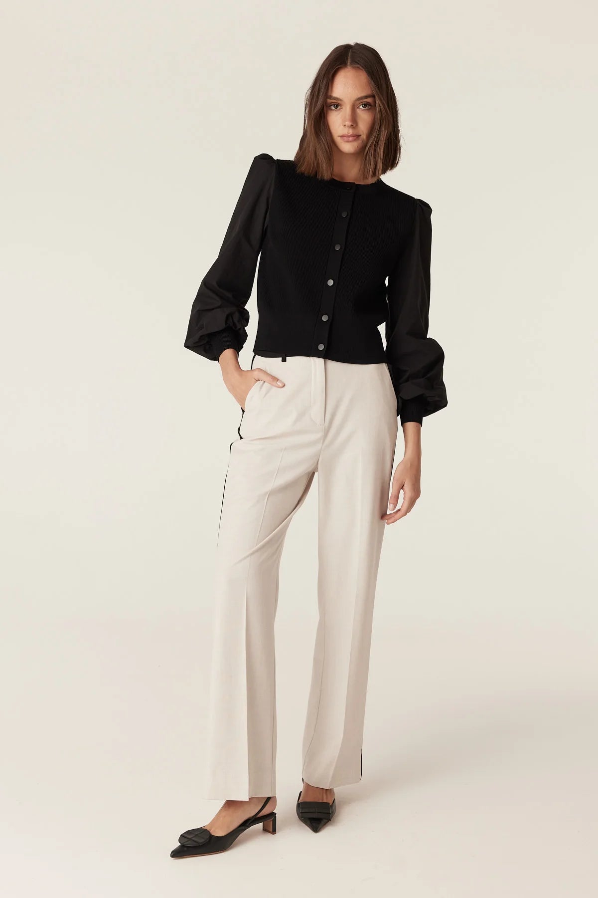 Woman wearing the Cable Melbourne Crepe Spring Cardigan in Black with cream and black wide-leg trousers