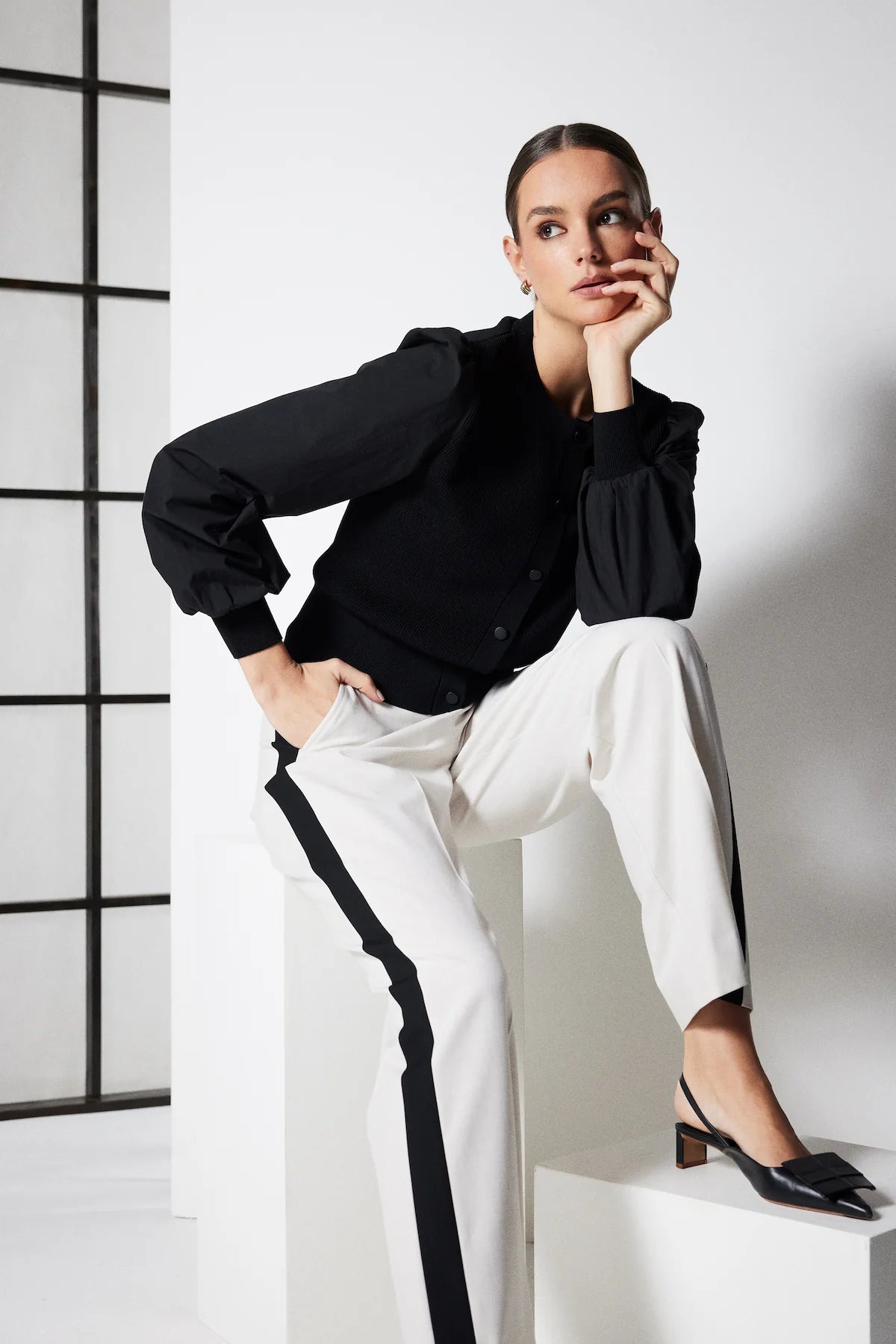 Cable Melbourne Crepe Spring Cardigan in Black styled with contrast-stripe trousers, seated pose